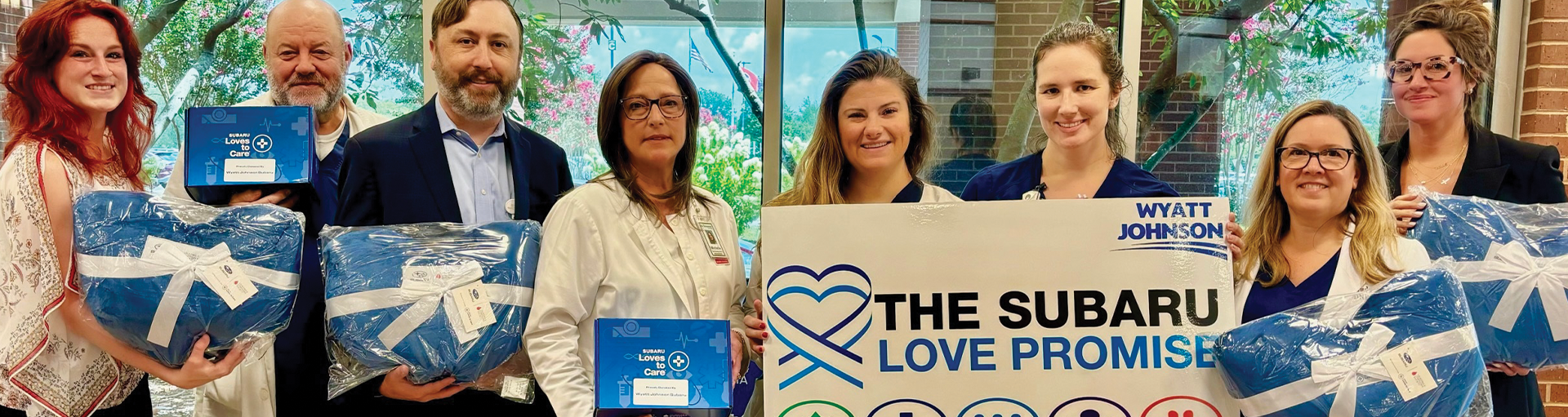 Wyatt Johnson Subaru employees holding up gifts for The Subaru Love Promise community outreach event.