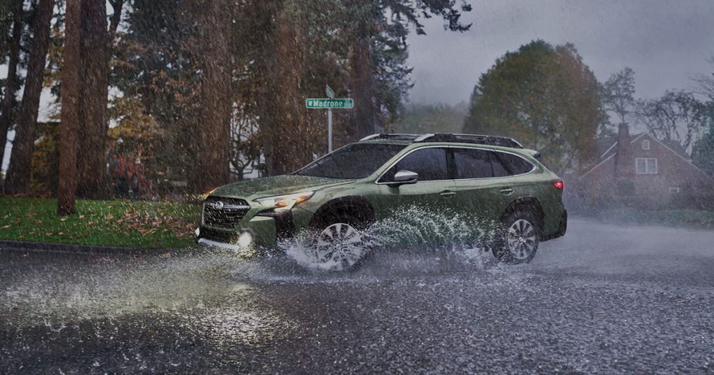 A Subaru Outback driving in heavy rainy weather.