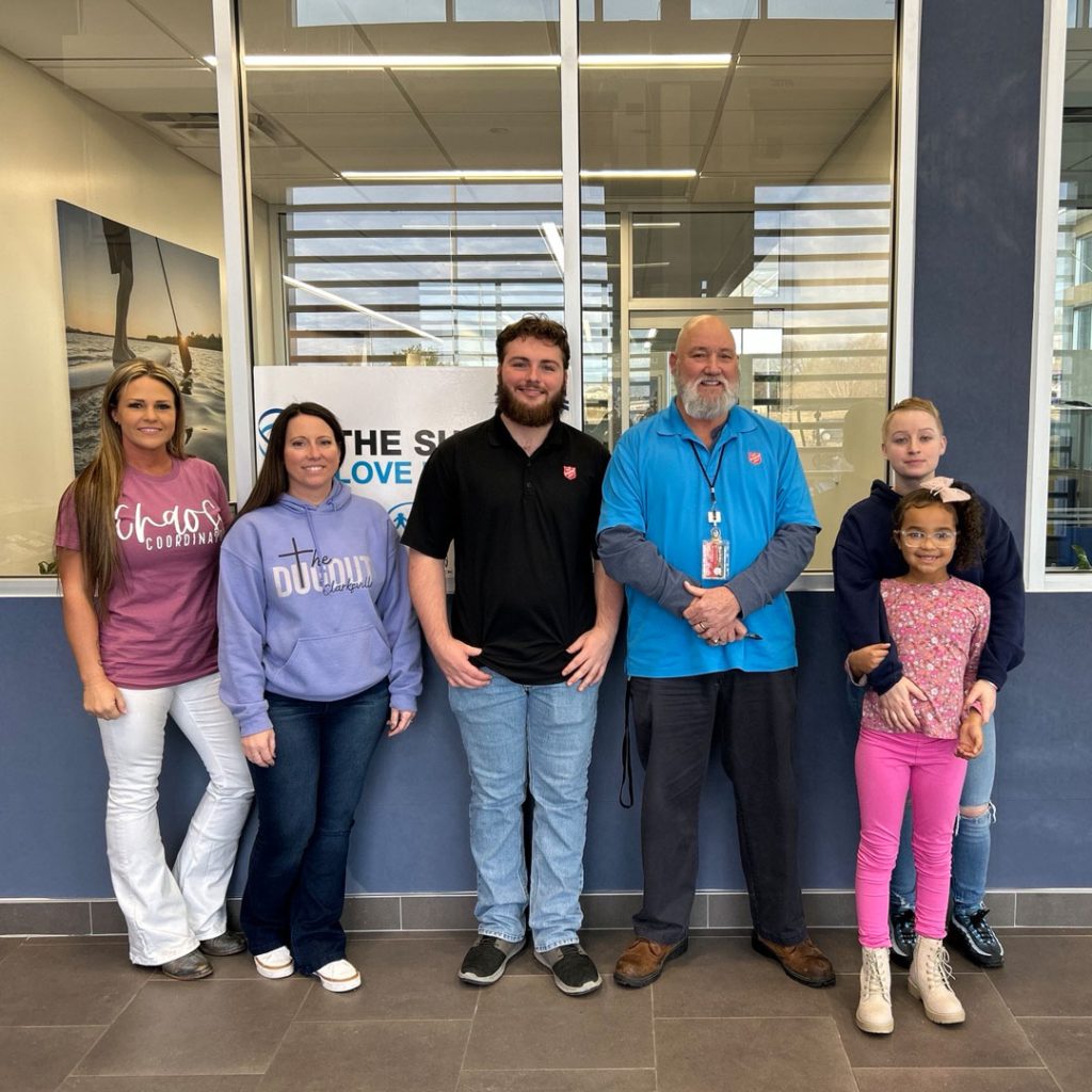 A group of people, ranging from men, women, to children, pose for a picture at Wyatt Johnson Subaru's dealership, which hosted a shoe and sock drive in Clarksville, TN.