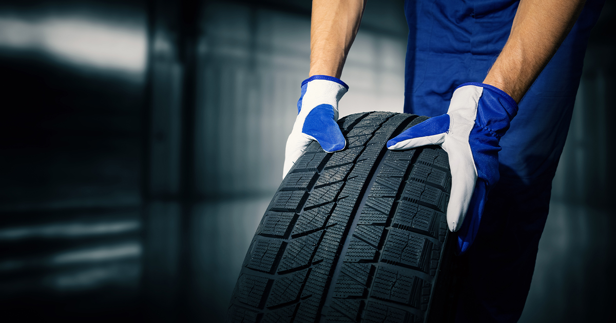 Close-up on a service technician carrying a tire