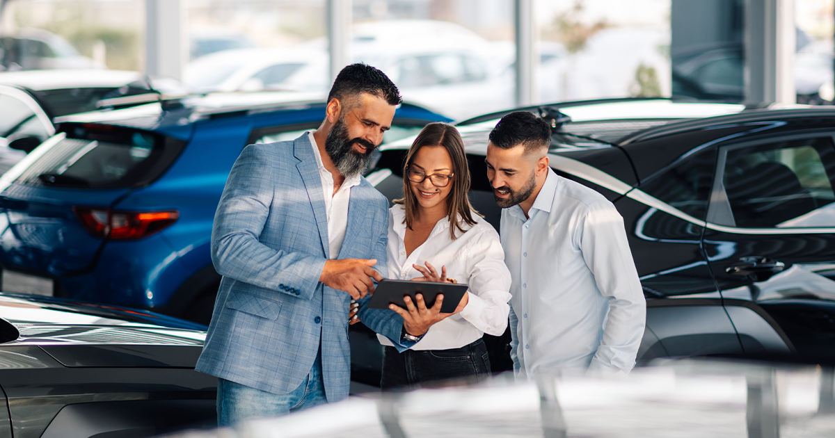 A salesperson at the dealership showing customers their offer on a tablet in the dealership
