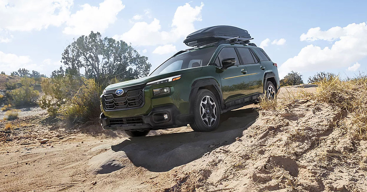 A Subaru Outback with camping accessories driving off-road.