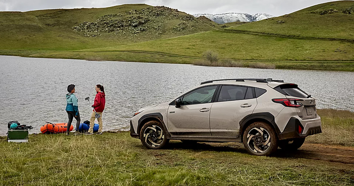 A white Subaru Crosstrek Hybrid parked by a lake.