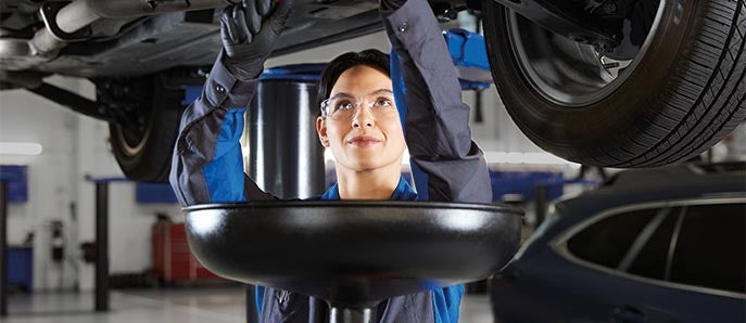 A Subaru service technician looking underneath a vehicle.